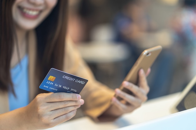 Close-up Aziatische vrouw die creditcard met mobiel voor online het winkelen in warenhuis gebruiken