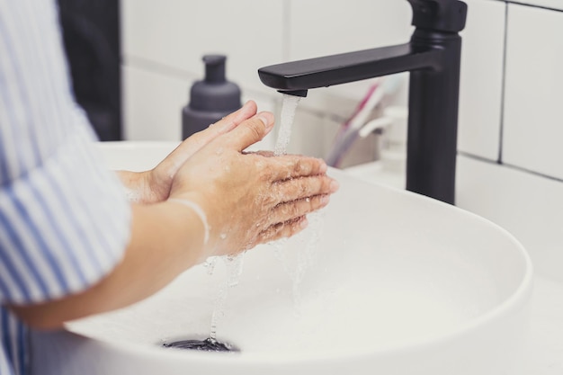 Close-up Aziatische vrouw handen wassen met kraanwater in de badkamer thuis