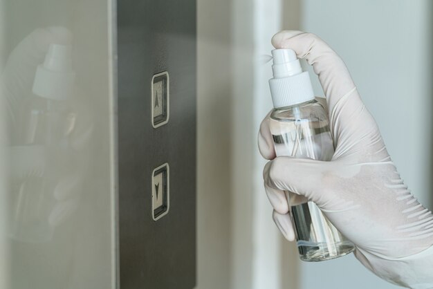 Close-up Aziatische vrouwenhand die medische handschoenen draagt en AntiBacterial Sanitizer Spray sproeit