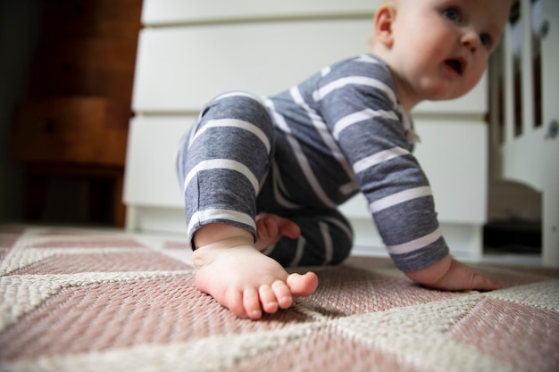 彼らが床を這うようにしようとしている赤ちゃんの足とつま先のクローズアップ
