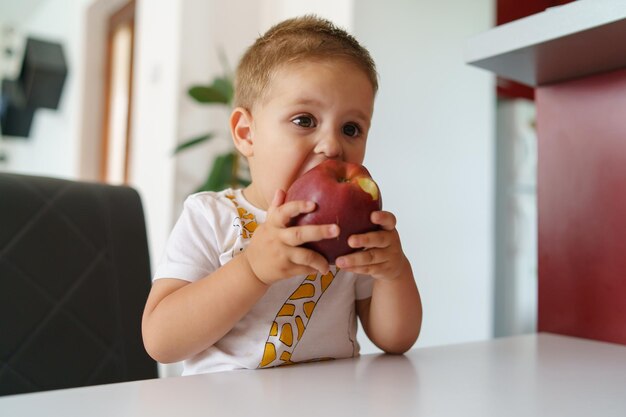 Photo close-up of baby boy eating apple at home