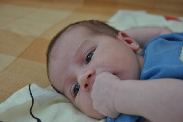 Photo close-up of baby boy lying on bed at home