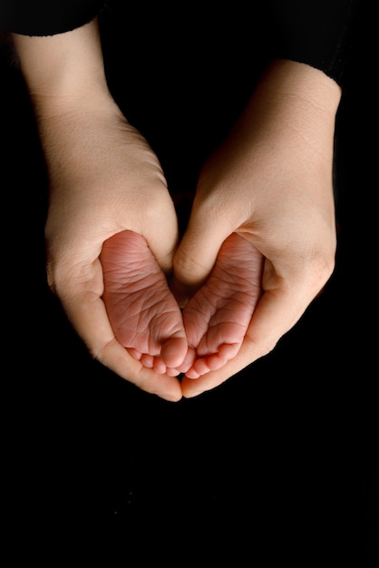 Foto close-up dei piedi del bambino nelle mani della madre