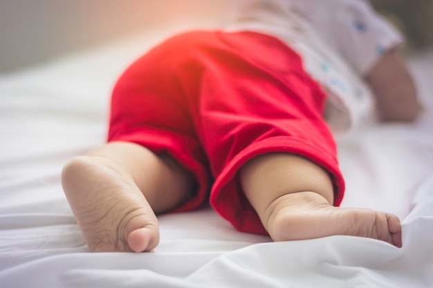 Close-up of a baby foot which wore red cotton trousers 