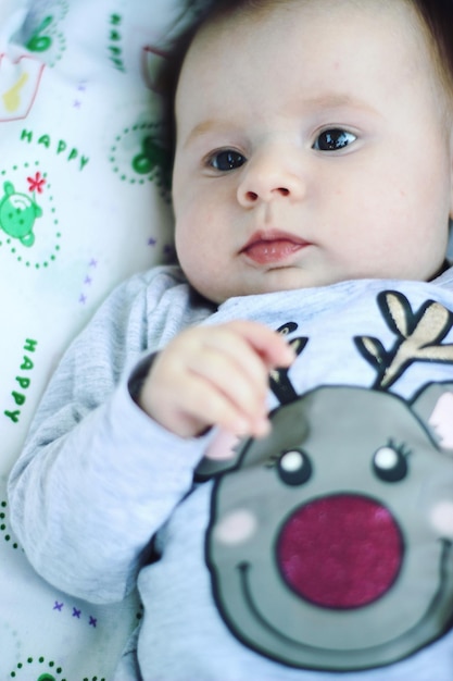 Photo close-up of baby girl lying on bed