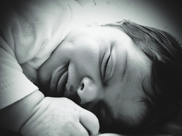 Photo close-up of baby girl sleeping on bed at home