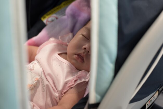 Photo close-up of baby girl sleeping in carriage