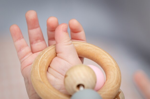 Close-up of a baby hand, playing with a wooden toy.