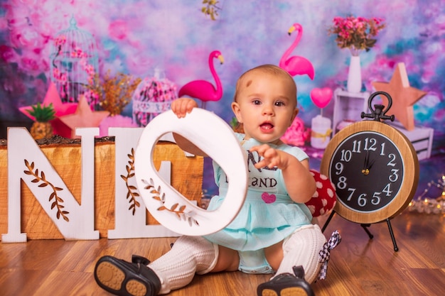 Photo close-up of baby holding birthday decorations