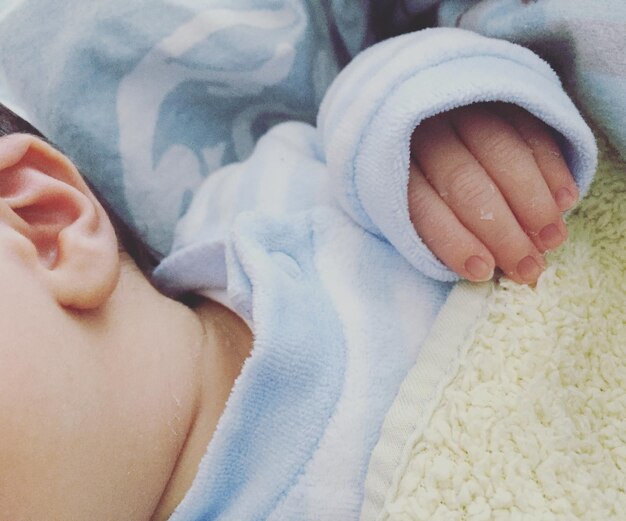 Photo close-up of baby lying down on bed at home