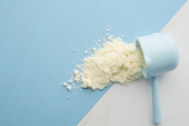 Close up of baby milk powder and spoon on tile background