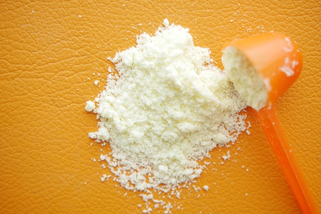 Close up of baby milk powder and spoon on tile background