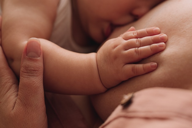 Foto primo piano della mano del bambino sul seno della madre. madre che allatta al seno.