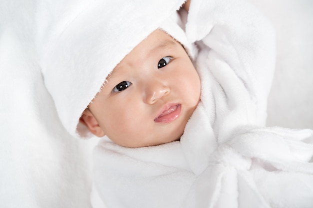 Close up baby in soft bathrobe on a bed