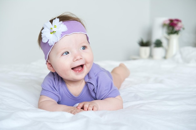紫の服を着てベッドに横たわって微笑む青い目をした赤ちゃんを接写