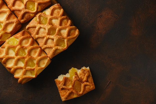 Close up background of fresh crispy puff pastry mini pies with pear and lime jam filling On a dark black and red textured background with fresh with pear and lime slices, from above, flatlay