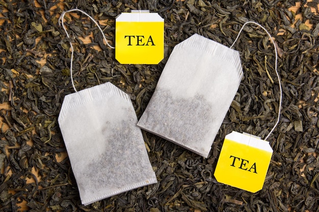 Foto primo piano di sfondo con tè nero essiccato e due bustine di tè