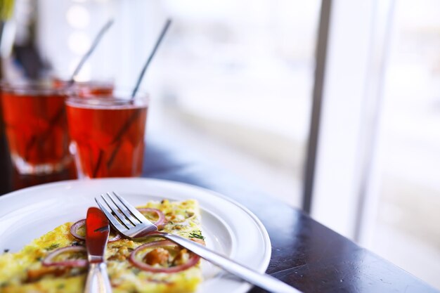 Primo piano di pizza con pancetta, succo d'arancia in un bicchiere sul tavolo in un bar in un ristorante