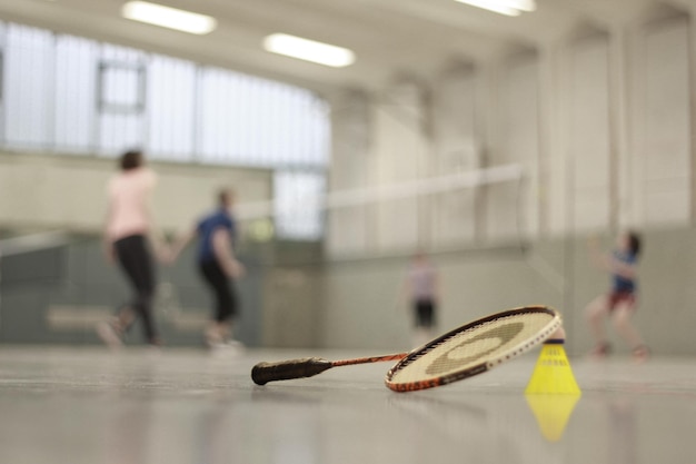 Foto close-up di racchetta di badminton e shuttlecock sul campo contro le persone