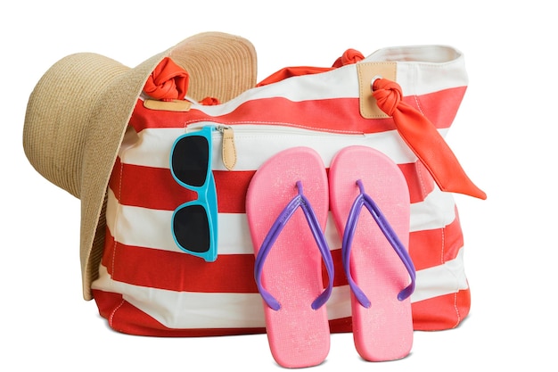 Foto close-up di una borsa piena di pantofole e occhiali da sole su uno sfondo bianco