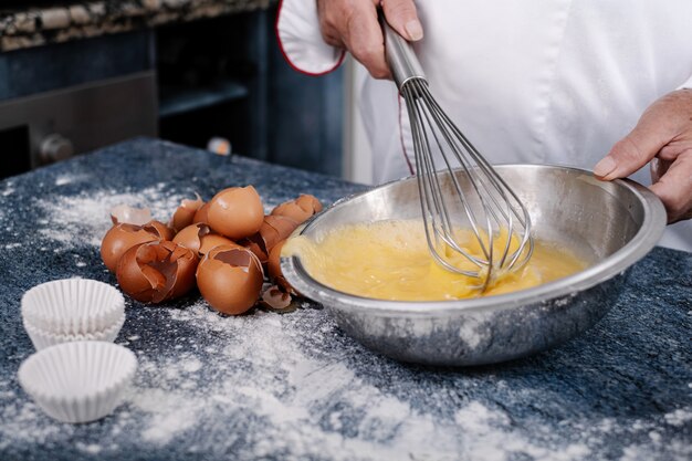 Close-up of a baker mixing eggs with a hand blender