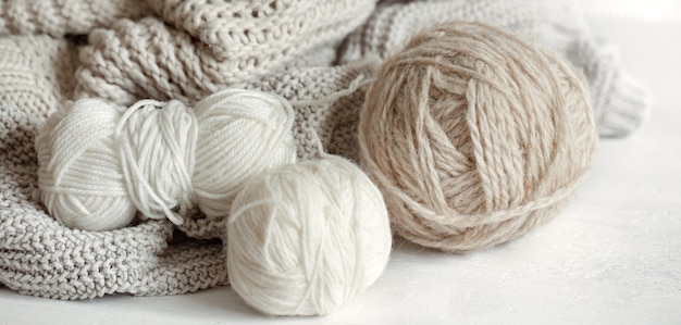 Close-up di gomitoli di lana in colori pastello e maglione a maglia accogliente
