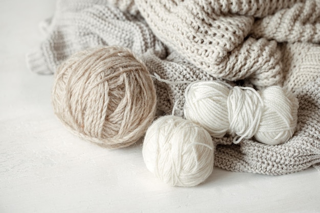 Close-up of balls of yarn in pastel colors and knitted cozy sweater