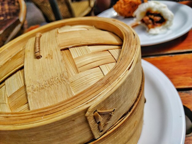 Photo close-up of bamboo steamer by food on table