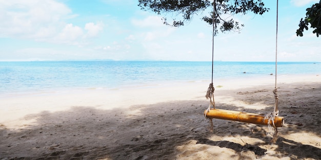 Close up bamboo swing hanging under big tree on the beach. 