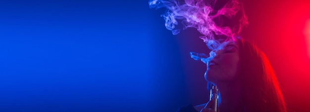 Close up banner portrait of vaping girl in neon blue and red light copy space