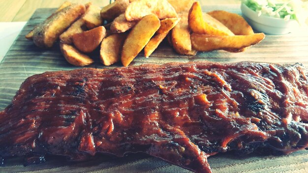 Close-up of barbecue pork ribs with fried potatoes