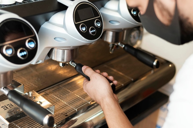 Foto primo piano barista con maschera che fa il caffè