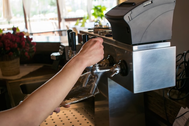 close-up of barman hand at beer tap pouring a draught lager beer