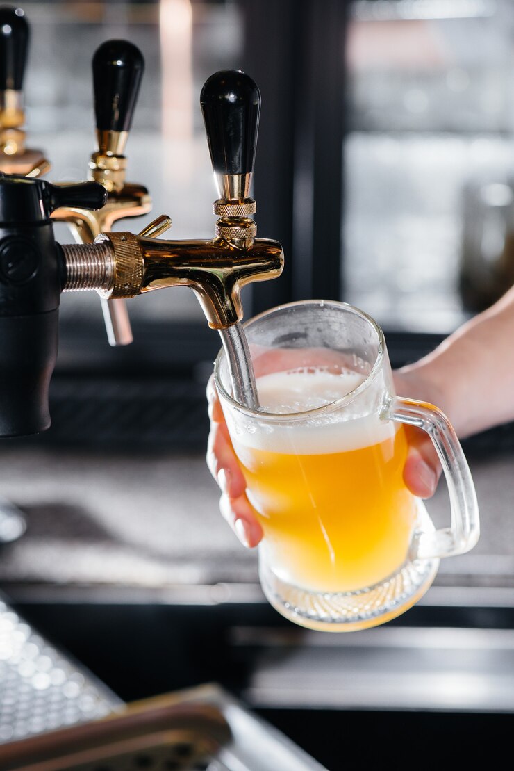 가벼운 맥주 한 잔을 채우는 바텐더의 클로즈업. 펍의 바 카운터.