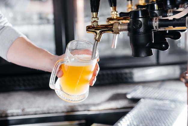 Close-up of the bartender filling a mug of light beer