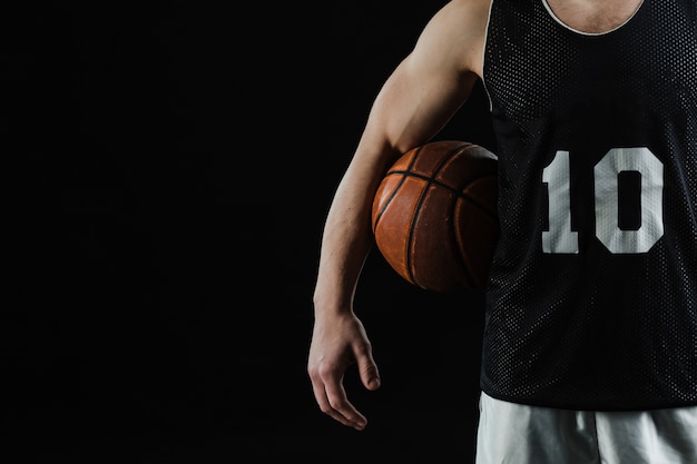 Photo close-up of basketball player with ball under his arm