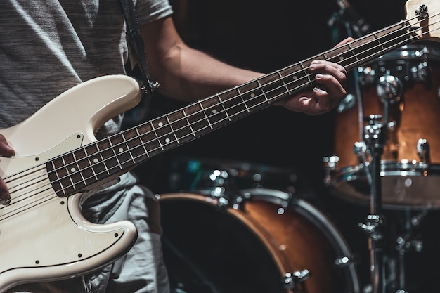 Close-up of a bass guitar in the hands of a musician in the process of playing.