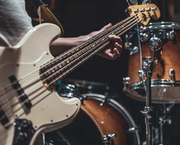 Close-up of a bass guitar in the hands of a musician in the process of playing.