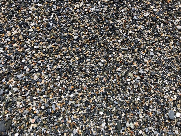 A close up of a beach with many different colored pebbles.