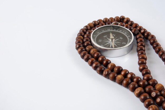 Close-up of bead necklace and navigational compass against white background