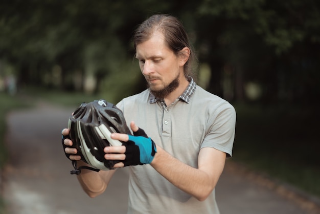 Primo piano di consegna barbuto uomo che indossa il casco in piedi con la bicicletta all'aperto, pronto per andare in bicicletta