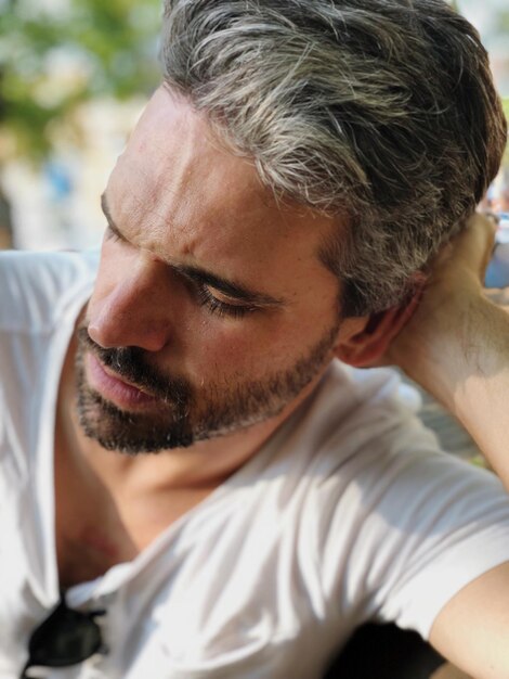 Foto close-up di un uomo adulto barbuto che si riposa all'aperto