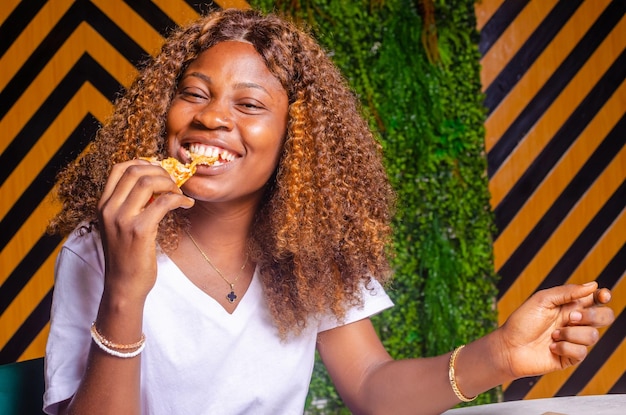 ピザを食べる美しいアフリカの女性のクローズ アップ