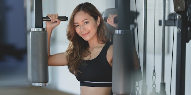 Close-up of beautiful Asian woman with tan and slim body exercise on machine 