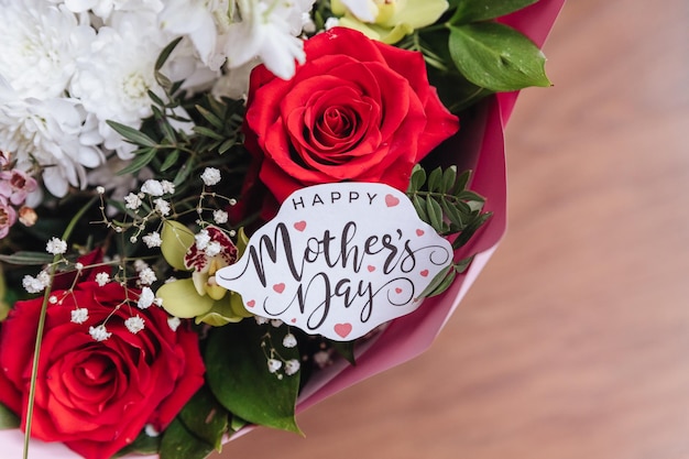 Close up of a beautiful bouquet of roses with a happy mothers day cardwhite gift card with the inscription concept of congratulations on the holidayBunch of flowers