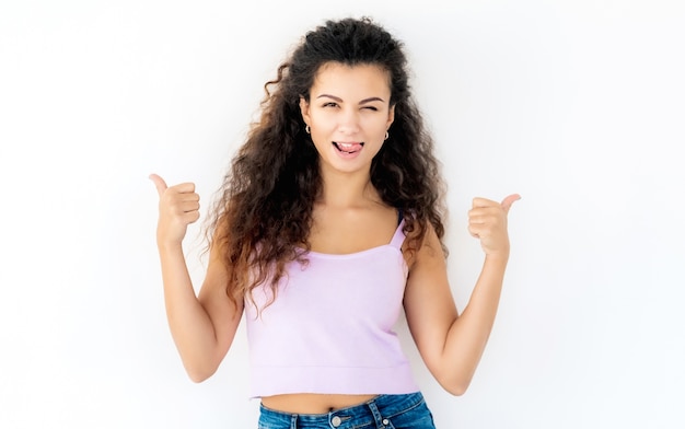 Primo piano sulla bella donna dai capelli ricci con i pollici in su