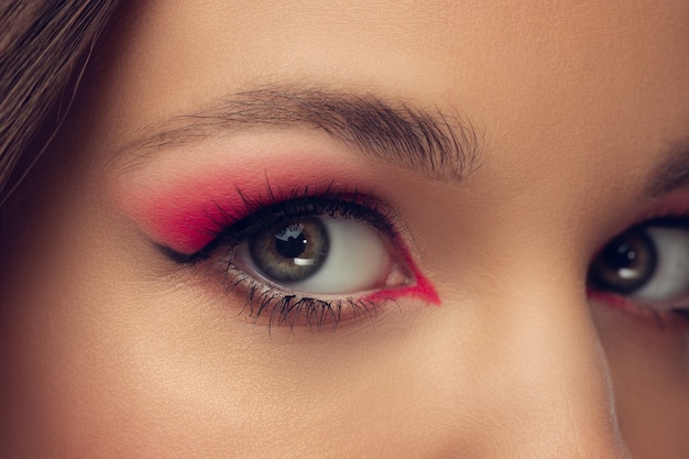 Foto primo piano di bellissimi occhi del viso femminile con trucco elegante e luminoso isolato su sfondo grigio studio