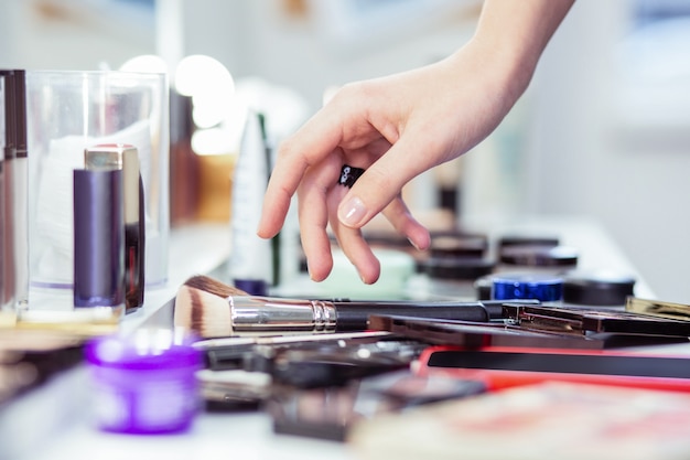 Close up of beautiful female hand touching a makeup brush