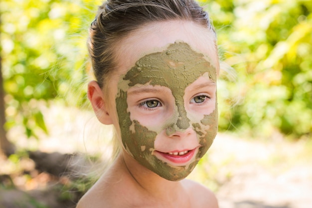 Photo close up of beautiful girl with facial clay mask