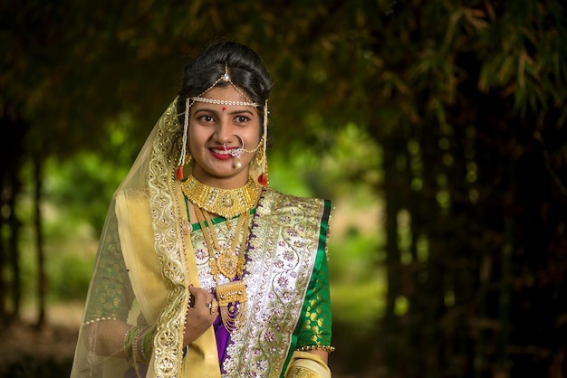 전통 사리 를 입은 아름다운 인도 신부 가 야외 공원 에서 포즈 를 취하고 있는 클로즈업